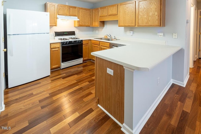 kitchen featuring light countertops, white appliances, a peninsula, and a sink