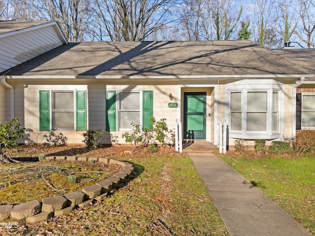 view of front facade with a shingled roof and a front lawn