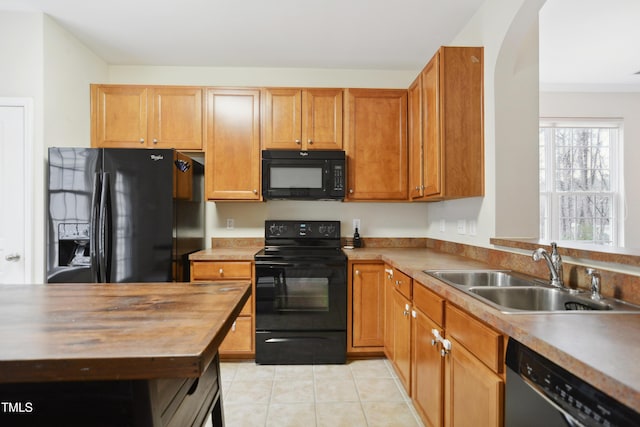 kitchen featuring brown cabinets, black appliances, light countertops, and a sink