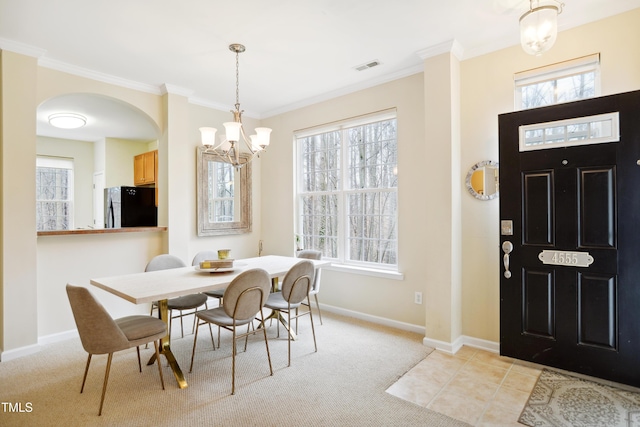 dining space featuring visible vents, ornamental molding, a wealth of natural light, and light colored carpet