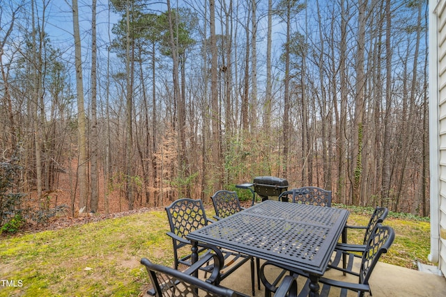 view of patio with outdoor dining space and a view of trees