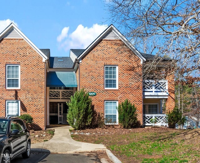 view of front of house with brick siding and roof with shingles