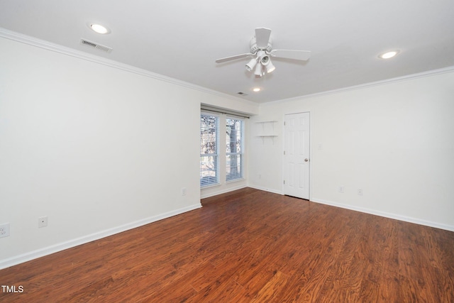 spare room featuring baseboards, wood finished floors, visible vents, and crown molding