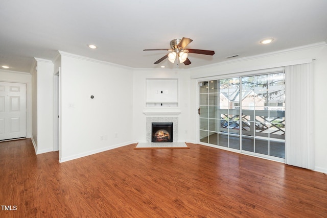 unfurnished living room with baseboards, ornamental molding, wood finished floors, and a lit fireplace