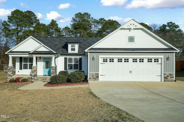 view of front facade featuring board and batten siding, a front yard, a garage, stone siding, and driveway