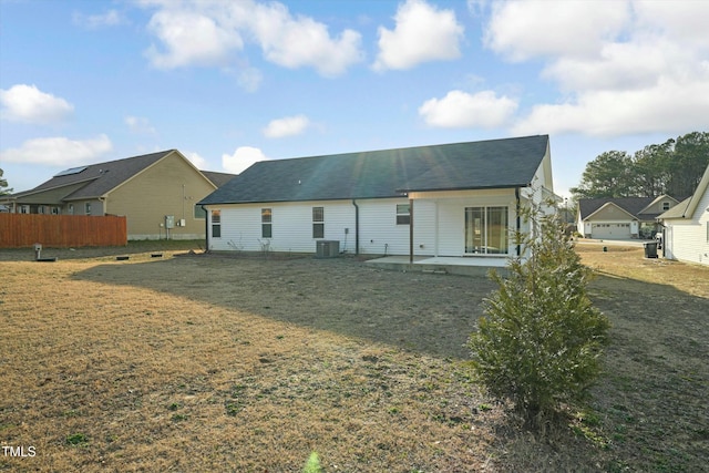 rear view of house with cooling unit, a patio, and a lawn