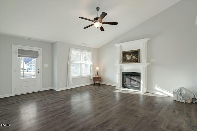 unfurnished living room featuring dark wood-style floors, vaulted ceiling, a fireplace with flush hearth, and a healthy amount of sunlight