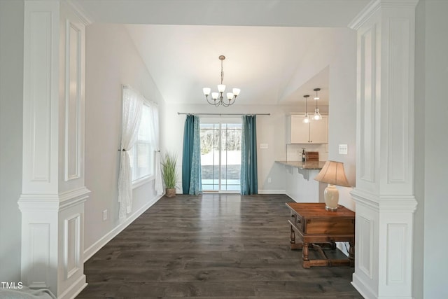 doorway featuring lofted ceiling, dark wood-type flooring, baseboards, and an inviting chandelier