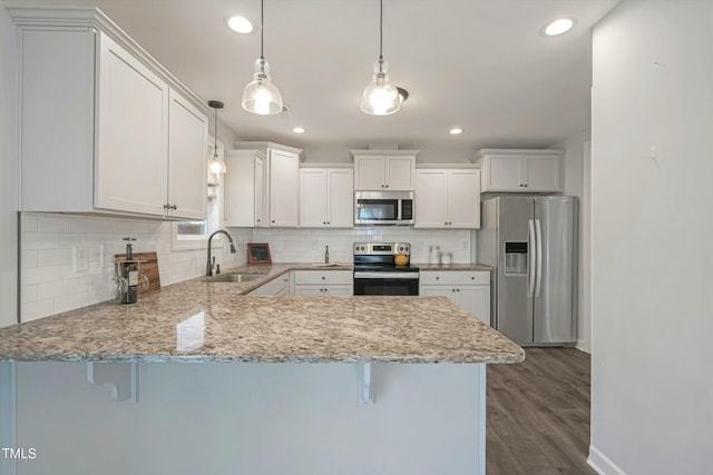 kitchen with white cabinetry, appliances with stainless steel finishes, a sink, and decorative light fixtures