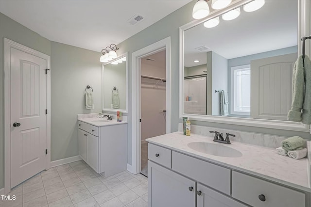 bathroom featuring a spacious closet, two vanities, a sink, and visible vents