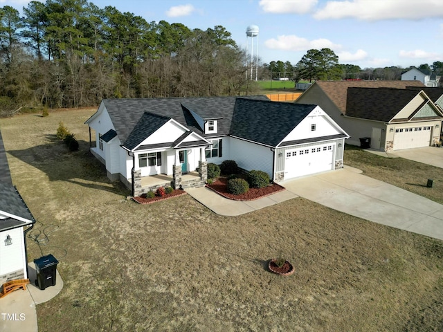 single story home featuring an attached garage, concrete driveway, a front lawn, and a porch