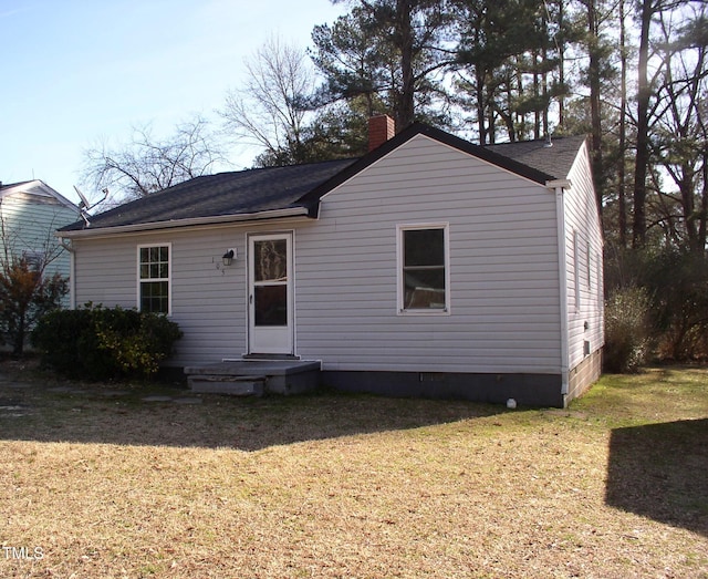 back of house featuring crawl space, a chimney, and a lawn