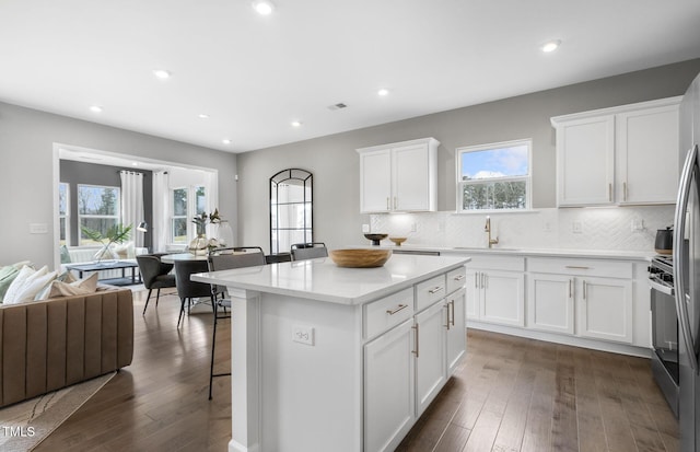 kitchen featuring sink, backsplash, a center island, white cabinetry, and dark hardwood / wood-style floors