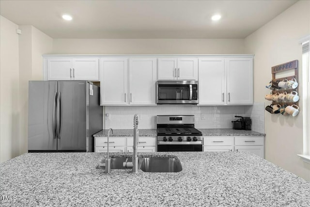 kitchen featuring white cabinetry, stainless steel appliances, tasteful backsplash, and sink