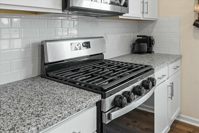 kitchen with tasteful backsplash, white cabinetry, light stone countertops, and stainless steel range with gas cooktop