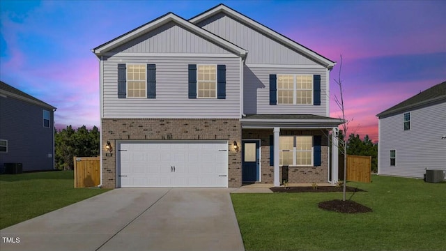 view of front of house with a garage, a yard, and central air condition unit