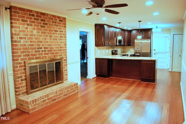 kitchen featuring stainless steel appliances, light hardwood / wood-style floors, dark brown cabinets, tasteful backsplash, and pendant lighting