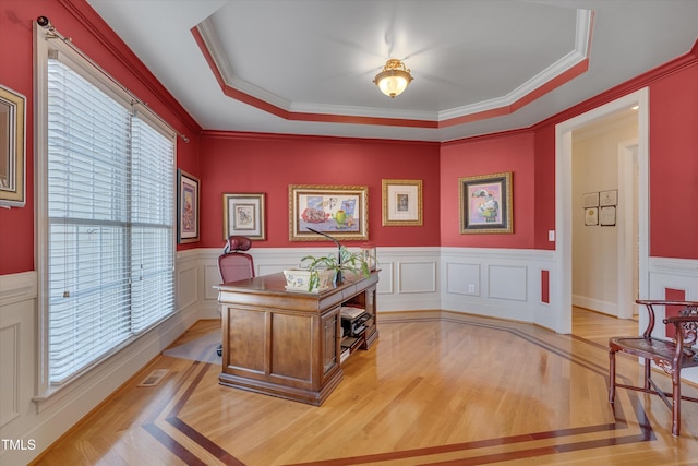 office featuring light wood finished floors, a tray ceiling, visible vents, and crown molding