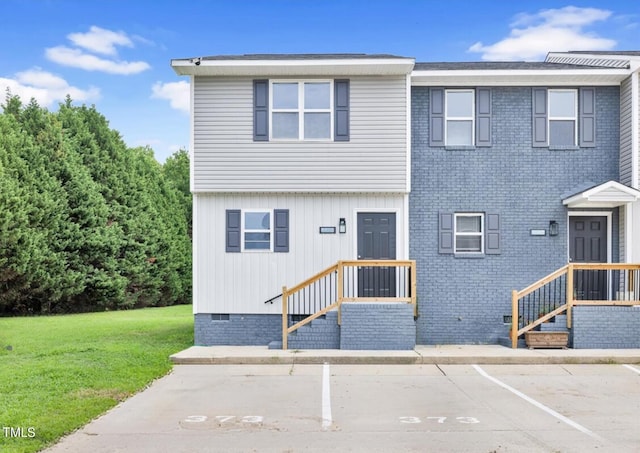 view of front of property with crawl space, uncovered parking, a front lawn, and brick siding