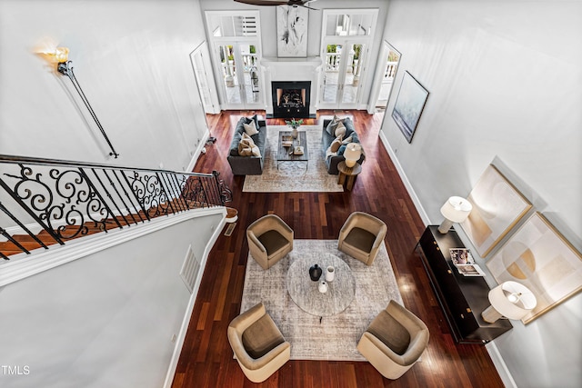 living area featuring visible vents, baseboards, a fireplace with flush hearth, stairs, and wood finished floors