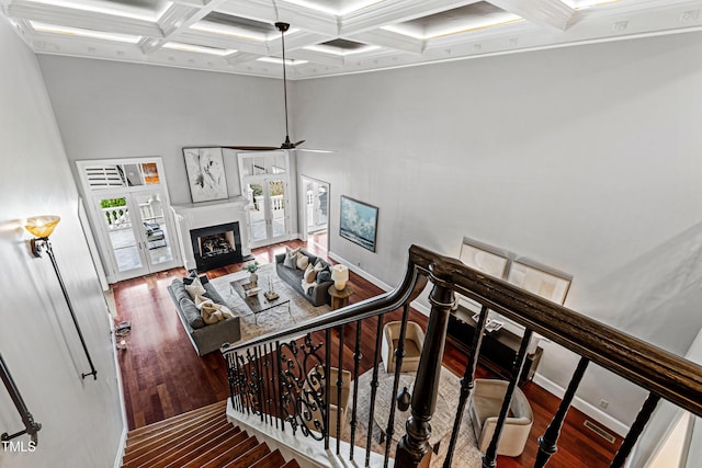 stairway with wood finished floors, a fireplace, coffered ceiling, and beam ceiling