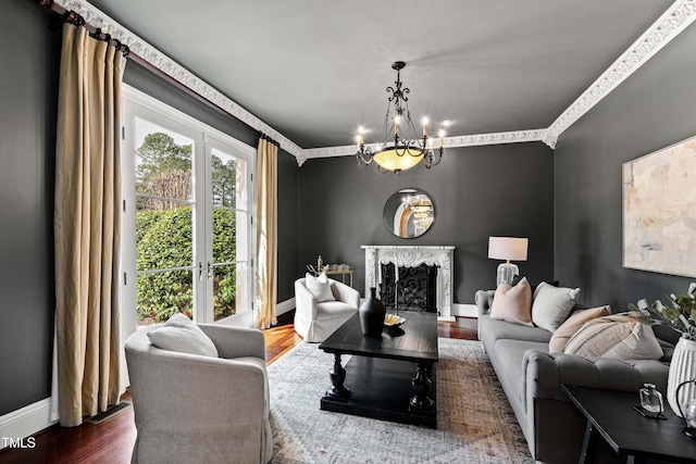 living area with a premium fireplace, baseboards, a notable chandelier, and dark wood-style floors