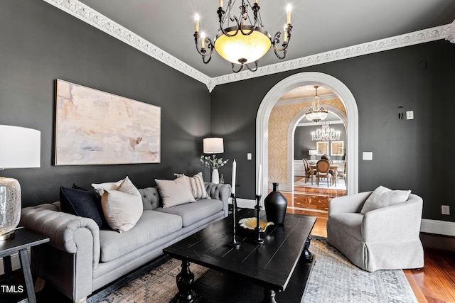 living room with baseboards, wood finished floors, arched walkways, and a chandelier