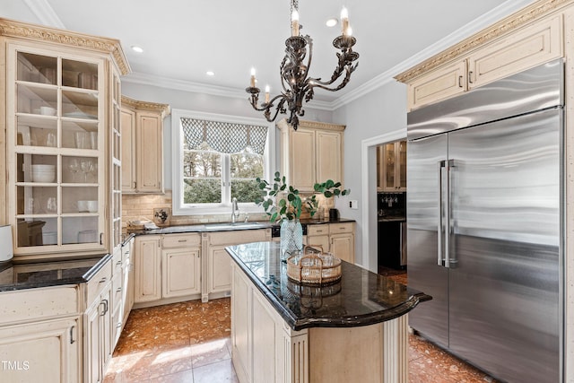 kitchen with a sink, cream cabinetry, stainless steel built in refrigerator, and crown molding