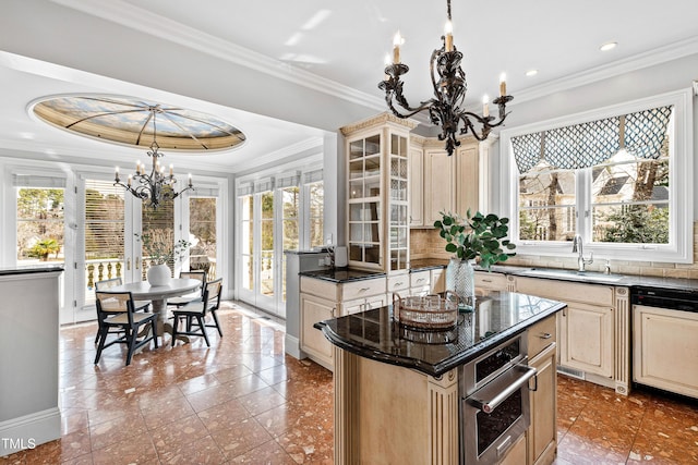 kitchen featuring oven, ornamental molding, a sink, cream cabinets, and a chandelier