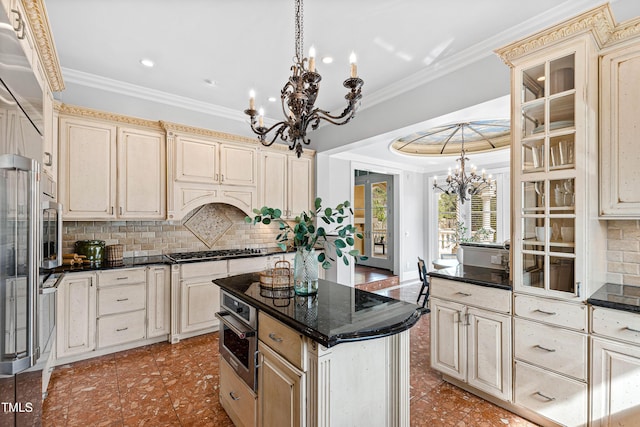 kitchen with gas cooktop, cream cabinetry, crown molding, stainless steel oven, and a notable chandelier