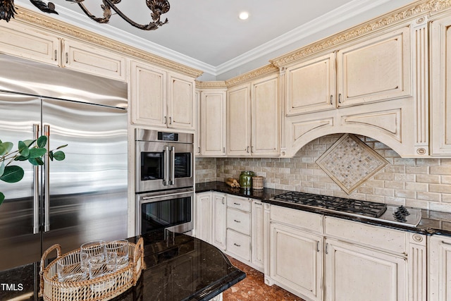 kitchen with ornamental molding, dark countertops, cream cabinets, appliances with stainless steel finishes, and decorative backsplash