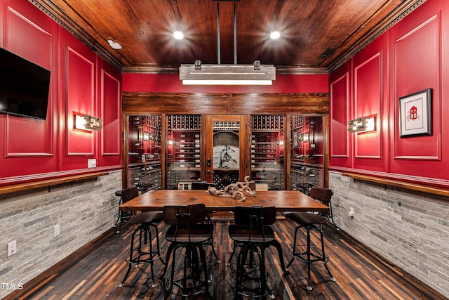 wine area featuring dark wood-type flooring, wooden ceiling, and crown molding