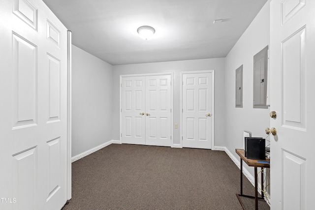 unfurnished bedroom with electric panel, dark colored carpet, baseboards, and a closet