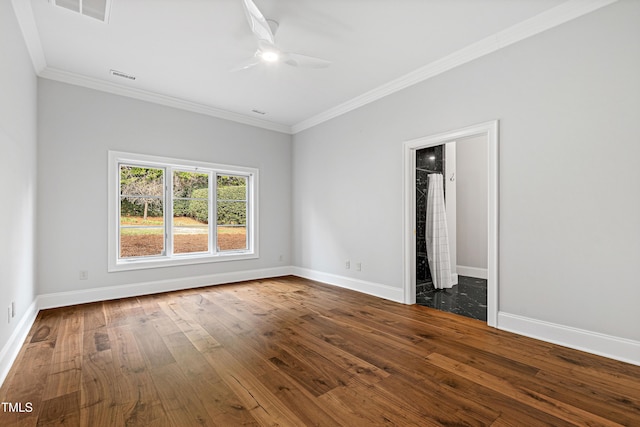 empty room featuring visible vents, ornamental molding, baseboards, and dark wood-style flooring