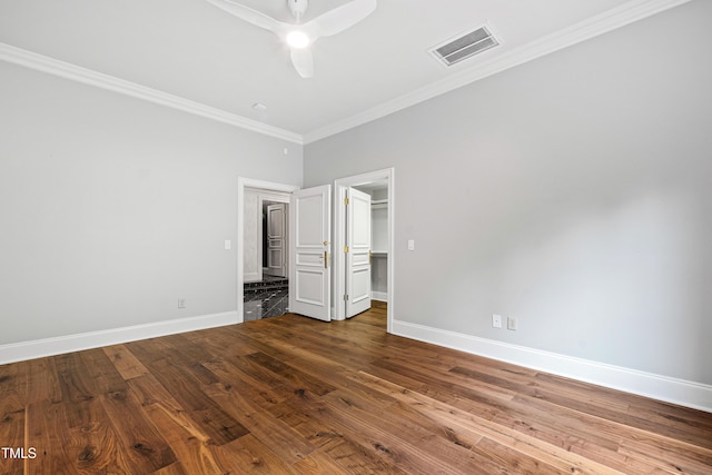 unfurnished bedroom with dark wood finished floors, visible vents, crown molding, and baseboards