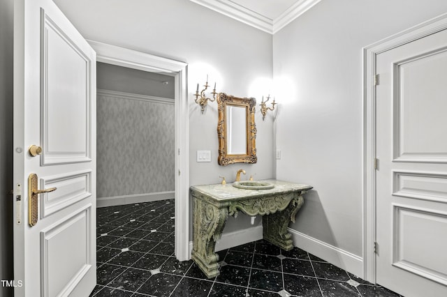 bathroom featuring a sink, baseboards, crown molding, and wallpapered walls