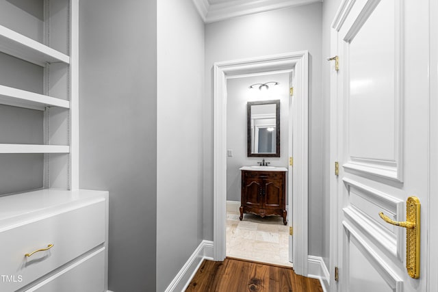 hall featuring a sink, baseboards, and dark wood-type flooring