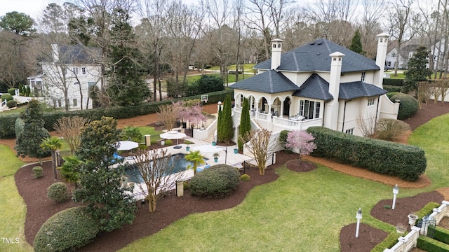 rear view of house with a yard, roof with shingles, stucco siding, and fence