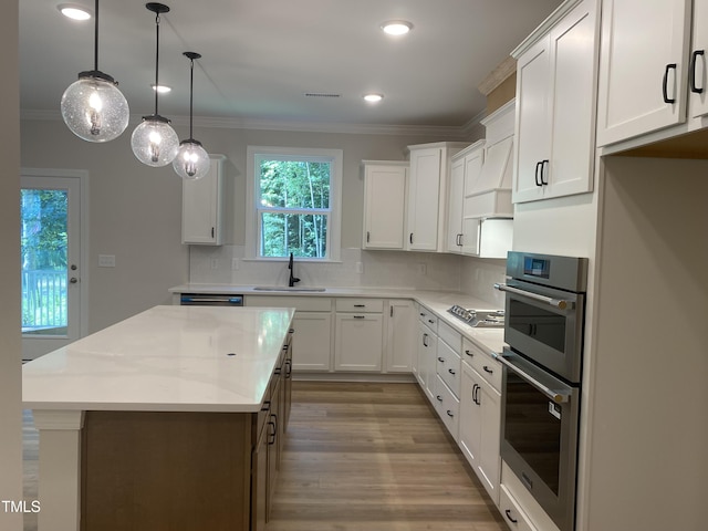 5036 Trotter Dr, Raleigh, NC 27603 - kitchen with appliances with stainless steel finishes, ornamental molding, a center island, tasteful backsplash, and light wood-type flooring