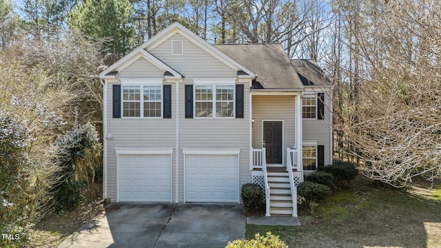 raised ranch with a garage, driveway, and stairs