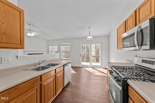 kitchen with dark wood-style floors, appliances with stainless steel finishes, light countertops, and a sink