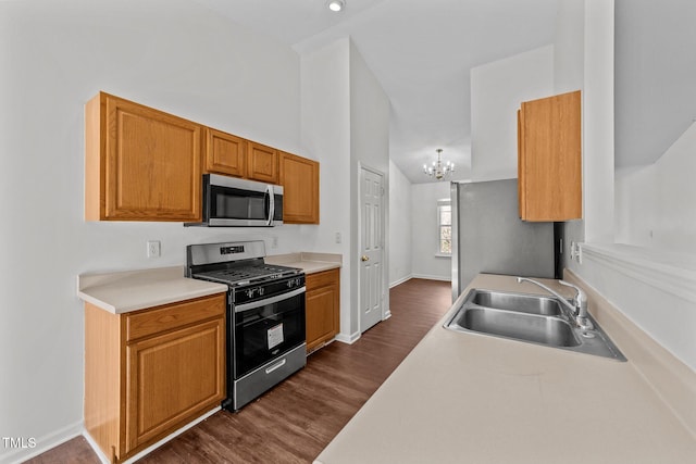 kitchen with a chandelier, stainless steel appliances, a sink, light countertops, and dark wood-style floors