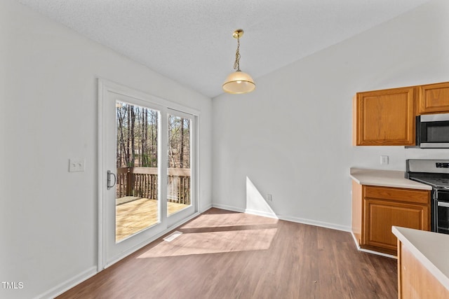 kitchen featuring a textured ceiling, dark wood-type flooring, light countertops, appliances with stainless steel finishes, and decorative light fixtures