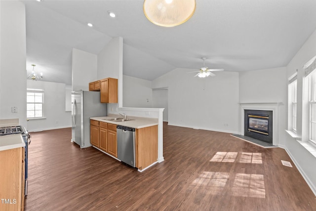 kitchen featuring ceiling fan with notable chandelier, light countertops, appliances with stainless steel finishes, and a glass covered fireplace