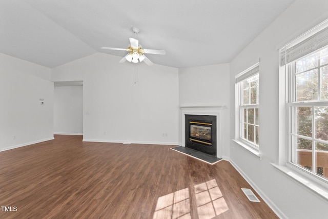 unfurnished living room featuring baseboards, visible vents, a glass covered fireplace, wood finished floors, and vaulted ceiling