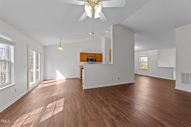 unfurnished living room with vaulted ceiling, dark wood-type flooring, visible vents, and baseboards