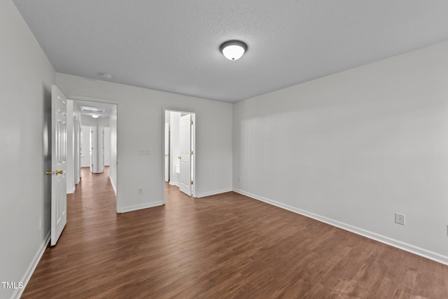 unfurnished bedroom featuring dark wood-type flooring, a textured ceiling, and baseboards