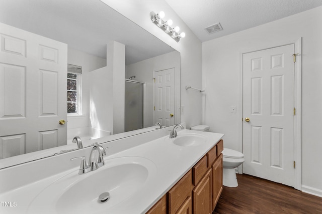 bathroom featuring a stall shower, double vanity, a sink, and wood finished floors