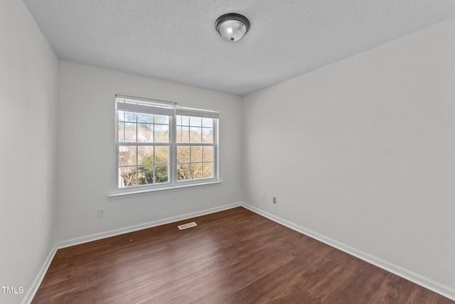 empty room featuring dark wood-style floors, baseboards, visible vents, and a textured ceiling