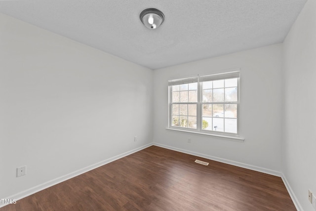 unfurnished room featuring a textured ceiling, dark wood finished floors, visible vents, and baseboards